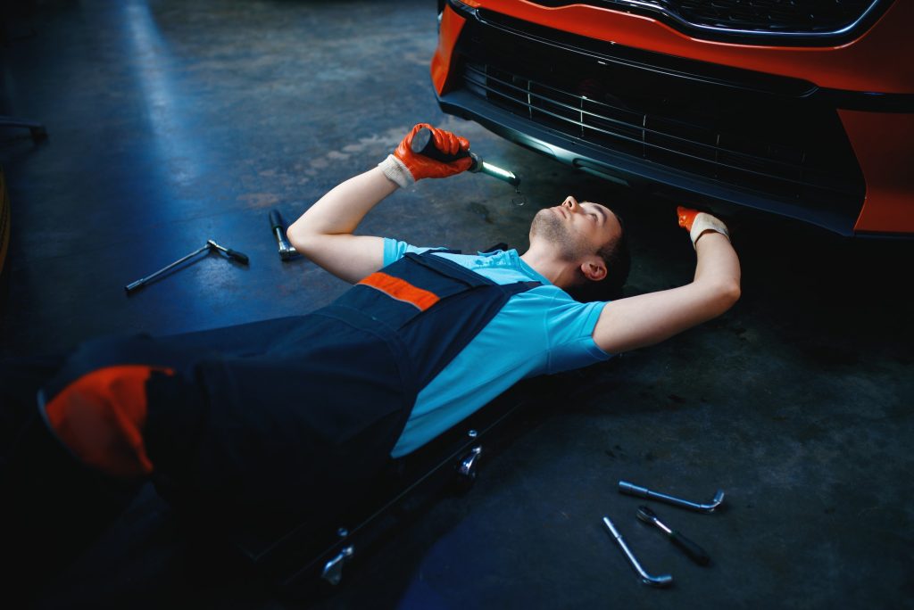Worker lying under the vehicle, car service